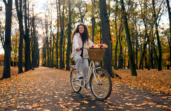 Woman cycling through an autumn park.
