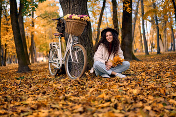 Fototapeta premium Smiling woman with bicycle in autumn park.