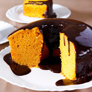 Brazilian carrot cake with a glossy chocolate glaze on a white plate.