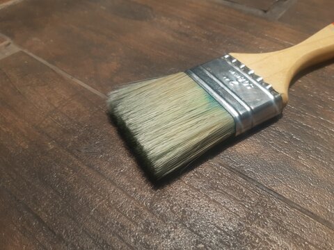 Paint brush with wooden handle on dark wood floor background