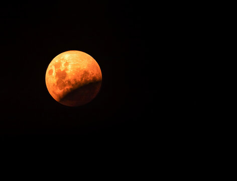 Partial lunar eclipse of a blood moon against a black night sky