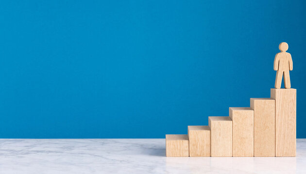 A wooden figure standing on top of a staircase made of wooden blocks against a blue background