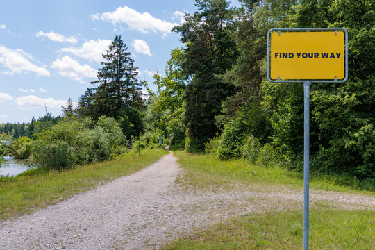 Yellow sign with text FIND YOUR WAY next to gravel path in green nature, life path decision and career orientation concept
