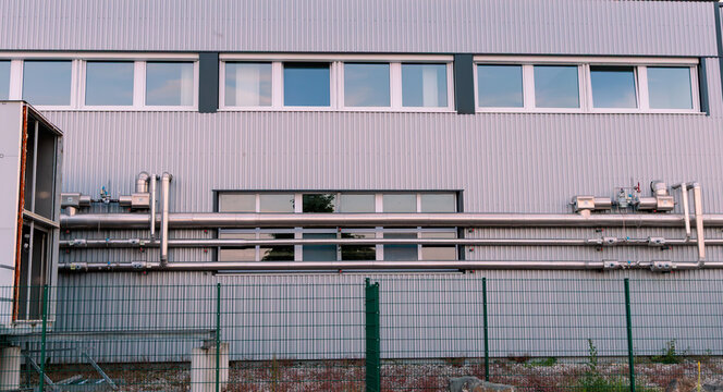 Modern industrial building facade with metal corrugated wall, stainless steel pipes and HVAC ventilation system, industrial infrastructure concept