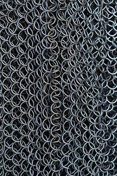 Closeup of shiny metal chainmail texture detailed background of interlinked rings, representing medieval armor and protection
