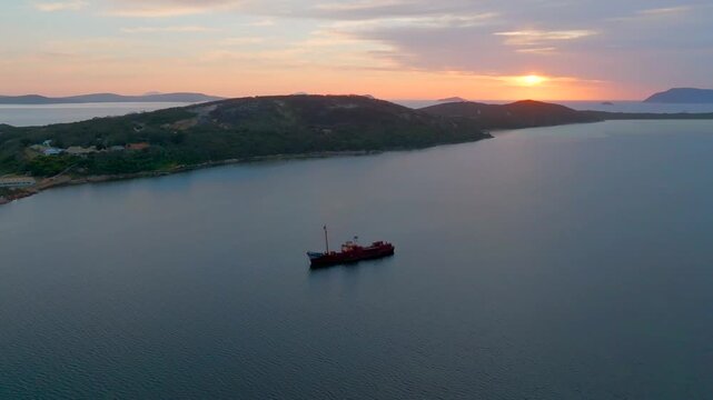 Aerial view of the Cheynes II Whale Chaser ship anchored in the calm bay at sunset with golden light reflecting on the water in Albany, Western Australia, Australia.