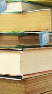 Animation of book icons over stack of books on wooden background