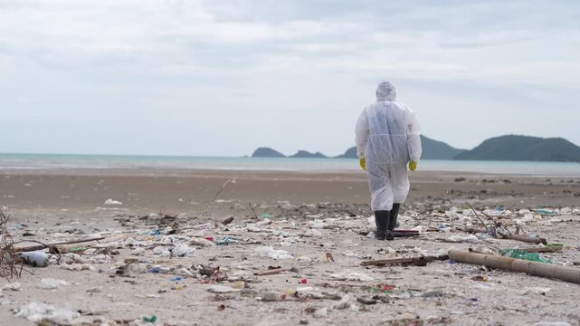 Coastal Pollution Plastic Waste Shoreline Person Protective Clothing Environmental Concern Beach Ocean Litter Marine Debris Cleanup Worker Facing Distant Island Under Overcast Sky