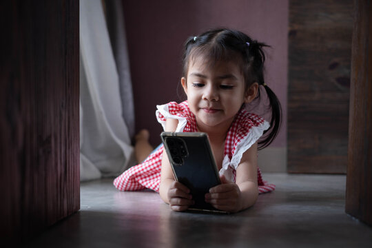 Cute young child using a smartphone at home, illustrating digital learning, online education, screen time, mobile technology, childhood curiosity, family lifestyle, and modern communication.