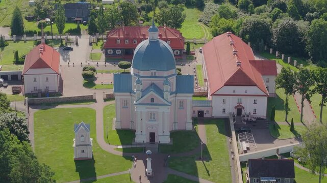 Aerial view of the historic Holy Trinity Church in Liskiava, featuring its prominent blue dome, red-roofed monastery buildings, and surrounding green lawns in Liskiava, Alytus County, Lithuania.