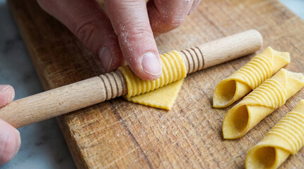 Naklejka premium Shaping Fresh Pasta Dough Tubes with Wooden Tool for Homemade Italian Cuisine