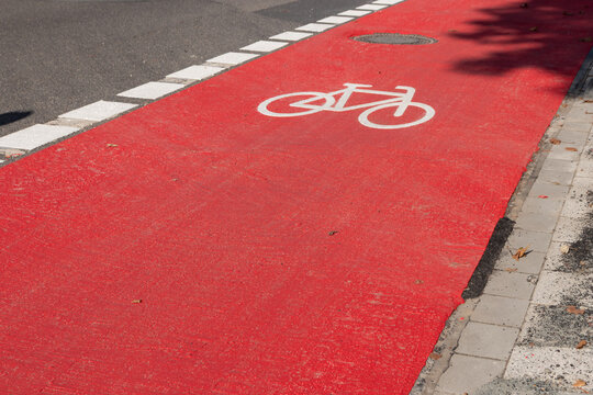 White bike sign on new red bicycle lane as sustainable city development with separated bikeway for safety in city traffic for bikers and cyclists. Sustainable transport by bike on new bike lane.