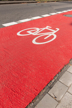 White bike sign on new red bicycle lane as sustainable city development with separated bikeway for safety in city traffic for bikers and cyclists. Sustainable transport by bike on new bike lane.