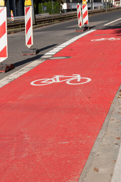 White bike sign on new red bicycle lane as sustainable city development with separated bikeway for safety in city traffic for bikers and cyclists. Sustainable transport by bike on new bike lane.