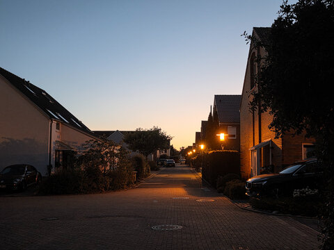 quiet residential street with illuminated streetlights and houses during peaceful blue hour twilight