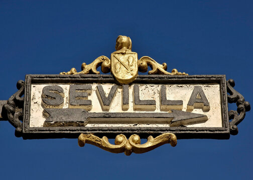 Sevilla street sign with ornate golden heraldry pointing direction. Spain - Sevilla