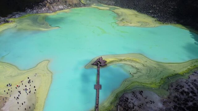 Aerial view of Kawah Putih Ciwidey with its turquoise volcanic lake, wooden pier, and sandy shores in Bandung, West Java, Indonesia.