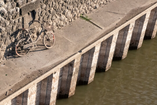 Recovering a sunken bicycle after throwing away a shared bike into a river, port or haven as environmental pollution. Muddy bike or dirty shared bike as thrown away bike sharing. Low tide brings bike.