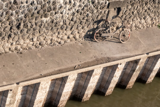 Recovering a sunken bicycle after throwing away a shared bike into a river, port or haven as environmental pollution. Muddy bike or dirty shared bike as thrown away bike sharing. Low tide brings bike.