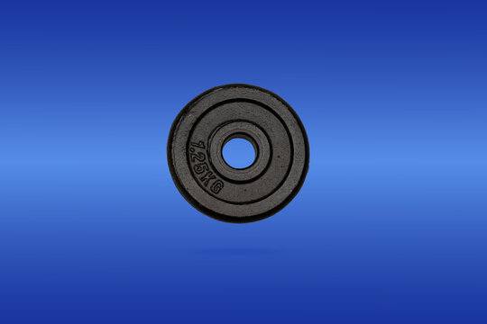 Weight plate on a solid blue background showing details and shape of the equipment for fitness