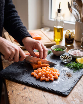 d&eacute;s de saumon cru sur une planche &agrave; d&eacute;couper 