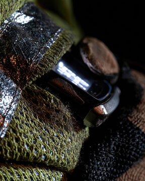 Wearable gas detector with a glowing blank screen clipped to a weathered hi-vis jacket at night, featuring copy space for EHS marketing