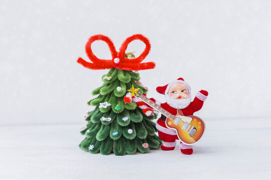 Santa with guitar and Christmas tree over blurred white background, Christmas card background idea, festive season concept