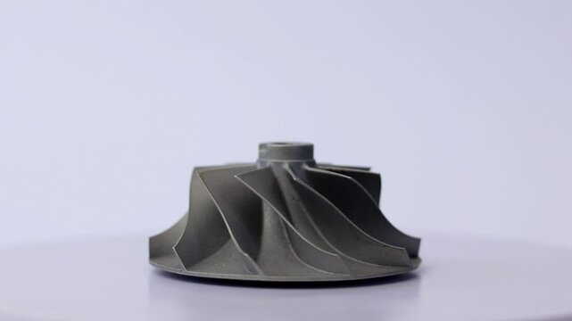 Car turbocharger billet aluminum compressor wheel impeller isolated on rotating display.