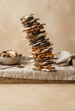 Stack of dried mushroom slices with small sticky tabs on a linen tray, featuring a precarious balance for health food and nutrition content with copy space