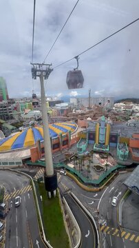 Genting Highlands, Malaysia: High-angle scenic view looking out from the Awana SkyWay gondola cabin over lush tropical rainforest, mountain slopes, and the Resorts World Genting resort complex. 