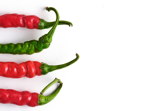 Fresh red and green hot chili peppers lined up horizontally on left white background.