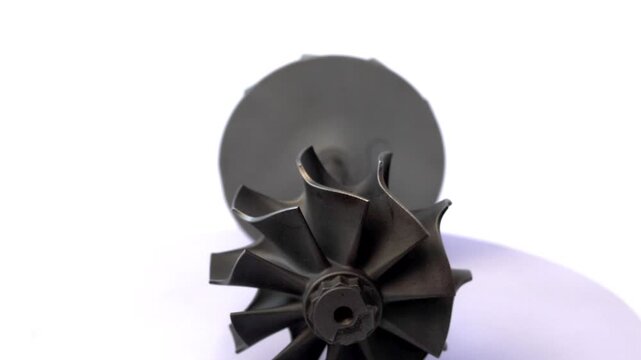 Automotive turbocharger turbine wheel rotor and compressor impeller shaft assembly on rotating display.