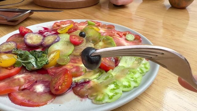 Fork Picking Black Tomato from Vibrant Heirloom Tomato Carpaccio Salad