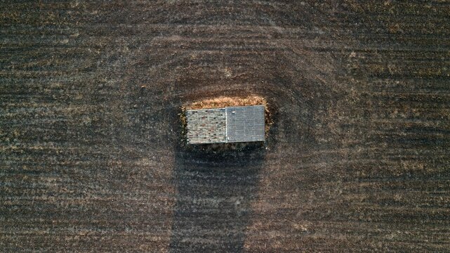 Aerial top down view of a stone farm hut in a harvested field with long shadows at sunrise, Valensole plateau, Provence, France