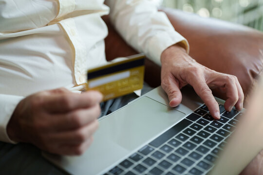 Man holding a credit card while using a laptop for online payment and shopping, representing secure digital transactions, e-commerce, internet banking, cashless purchasing and modern finance.