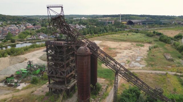 Aerial view of the abandoned Clabecq steelworks featuring rusty industrial structures and a headframe set within an overgrown landscape in Tubize, Wallonia, Belgium.