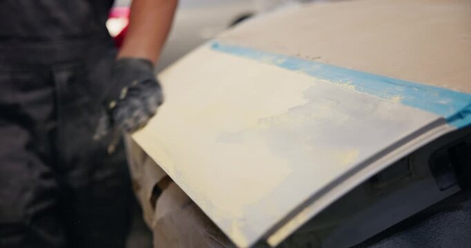 Slow motion mechanic sanding car door in auto body workshop during repair process, garage fix.
