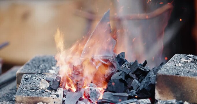 Blacksmith work Burning charcoal and glowing embers in brick fire pit in forge.