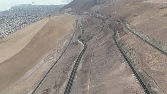 Aerial footage of a winding paved highway cutting through the barren and arid landscape of the Atacama Desert in Chile.