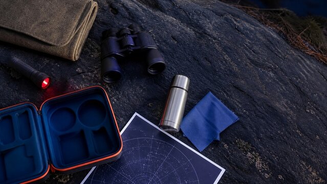 A close up view of various outdoor gear resting on dark textured rock; it suggests preparation for an adventure or hiking trip; the items imply rugged exploration awaits