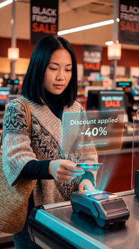 Focused customer paying by card as augmented reality discount confirmation hologram appears