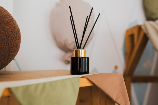 A diffuser is a means to eliminate unpleasant odors in the living room or office. On a shelf or coffee table in the living room there is a jar of dark glass with aromatic oil and synthetic sticks