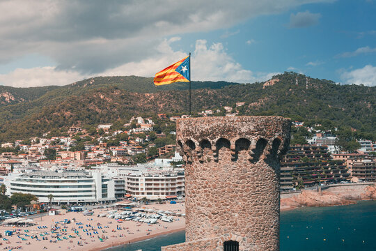 Estelada flag above coastal tower in Catalonia Spain with Costa Brava landscape and seaside resort town. Editorial travel image about Catalan independence and regional identity. High quality photo