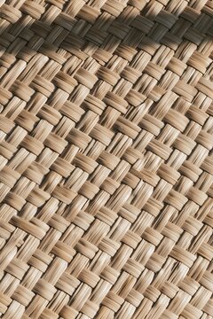 Closeup of woven natural rattan texture on a Tropical Modernism lounge chair, showcasing intricate interlocking fibers in warm light