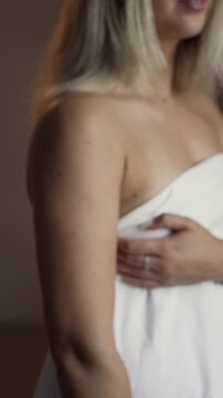 An unidentified adult woman wrapped in a sheet holds out her hand with a sealed condom to protect herself from AIDS and prevent accidental pregnancy.
