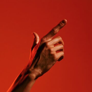 Hand pointing upward with dramatic red lighting against a plain background