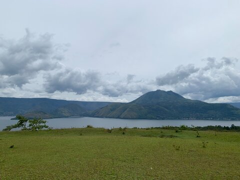Scenic landscape view of lake Toba with green hills and mountains under a cloudy sky in North Sumatra, Indonesia
