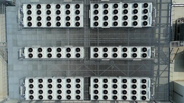 Aerial view of industrial cooling fans and HVAC ventilation units arranged in rows on a flat rooftop in Luton, England, United Kingdom.