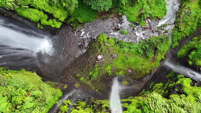 Aerial view of Curug Ciarjuna waterfall surrounded by lush tropical forest and greenery in Garut, West Java, Indonesia.