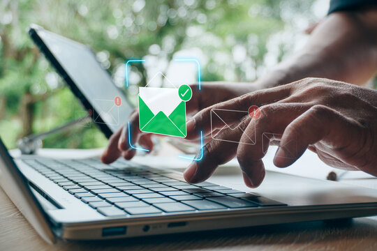Hands typing on laptop keyboard with verified secure email hologram icon passing spam and phishing filter, concept of cybersecurity, safe email communication, and anti-fraud protection.